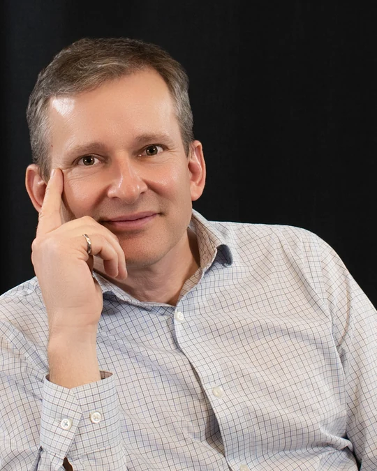 Seated professional portrait against a dark backdrop