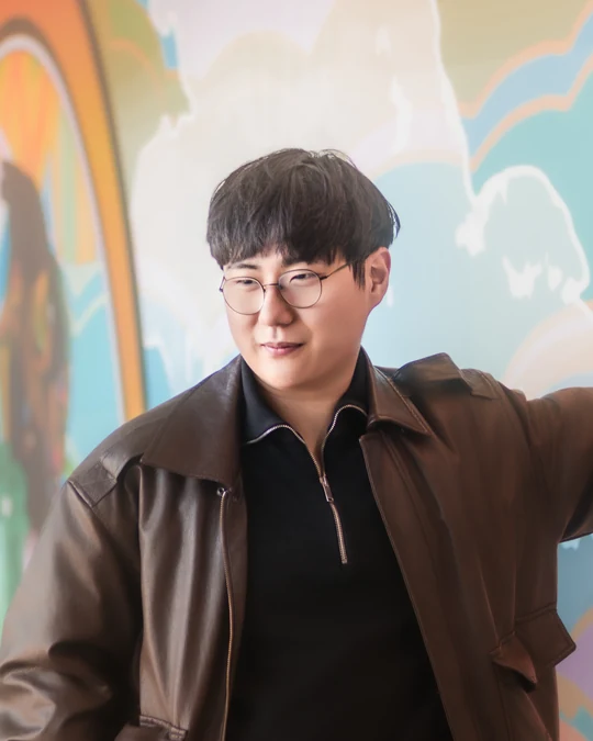 Environmental portrait in a brown jacket beside a mural