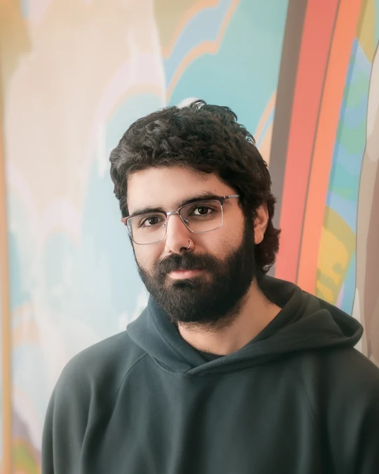 Close portrait of a man wearing glasses against a colourful background